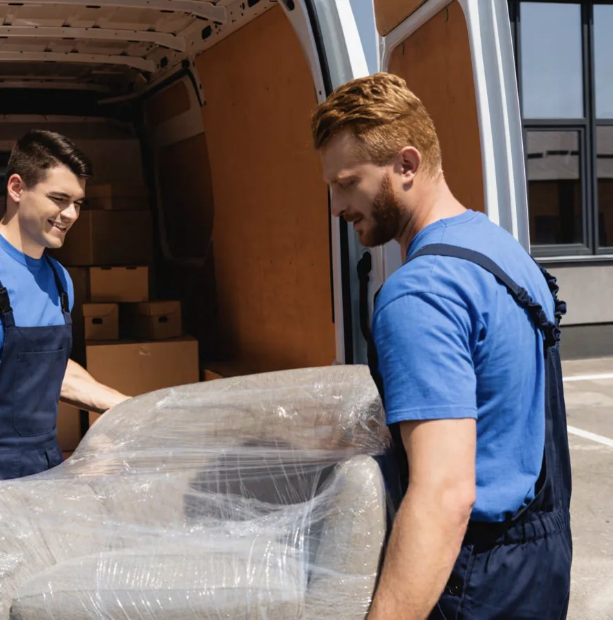Movers carrying a sofa wrapped in plastic